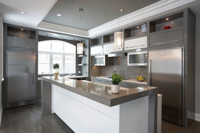 A grey and white modern kitchen with two large column refrigerators.